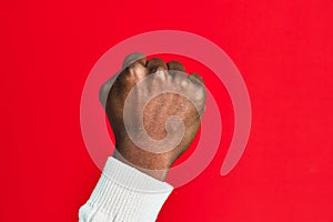Arm and hand of african american black young man over red isolated background doing protest and revolution gesture, fist