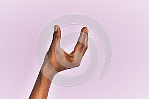 Arm and hand of black middle age woman over pink isolated background picking and taking invisible thing, holding object with