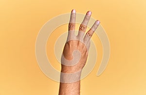 Arm and hand of caucasian man over yellow isolated background counting number 3 showing three fingers
