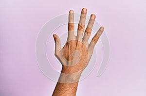 Arm and hand of caucasian young man over pink isolated background counting number 5 showing five fingers