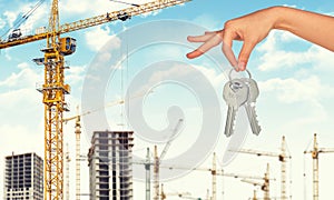 Arm holding keys on construction site background