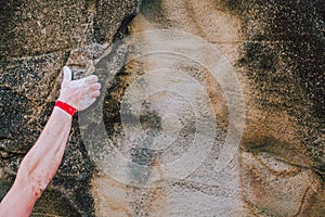 Arm of a rock climber man gripping the crack wall