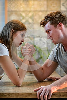 Arm wrestling challenge between young man and woman, couple household conflict and fight