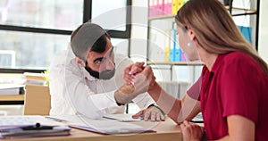 Arm wrestling of young man and woman and wanting to surpass company competitor