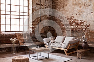 Armchair in beige couch in living room interior in wabi sabi style with flowers on table and window photo