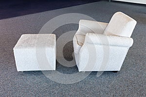Armchair with white textile upholstery and seperate foot-rest