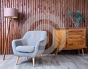 Armchair and wooden cabinet near wooden planks paneling wall. Loft interior design of modern