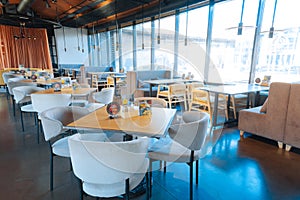 Armchairs standing near tables in restaurant with French windows