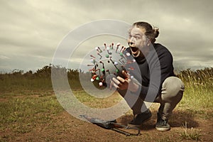 Armed civilian fighting with model of coronavirus virion outdoor on meadow