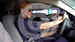 Armed female police officer in sunglasses driving to crime scene, on duty