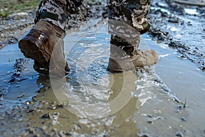 Armed Forces of Ukraine. Ukrainian soldier. Brown military boots on mud and puddle