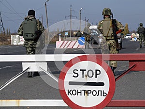 Armed Ukrainian border guards check vehicles on  the security checkpoint. War in Donbass. The inscription on the road sign - Stop. photo