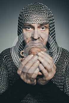 Armed man in chain armor with clay jug posing for portrait in studio