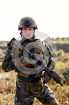 Armed special forces soldier with rifle in field during military operation, portrait, alone