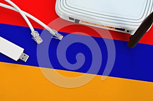 Armenia flag depicted on table with internet rj45 cable, wireless usb wifi adapter and router. Internet connection concept