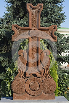 Armenian cross. Sculpture. In the park. Against the backdrop of green trees and sky. Surb Khach