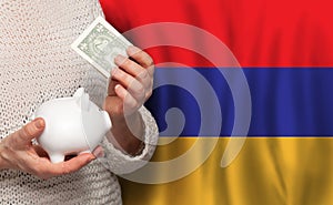 Armenian woman with money bank on the background of Armenia flag. Dotations, pension fund, poverty, wealth, retirement concept