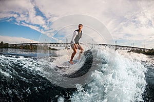 armless man ride the wave on wakeboard against the background of cloudy sky.