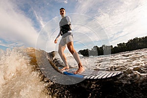 armless man is surfing on surfboard trails behind boat. Wakesurfing on the river