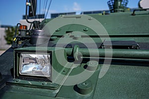 Armoured vehicle front green steel plating, close-up detail to small head light