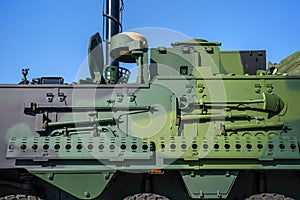 Armoured vehicle side green steel plating, close-up detail to pole, shovel and other tools mounted on wall
