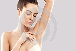 Armpit epilation, lacer hair removal. Young woman holding her arms up and showing clean underarms