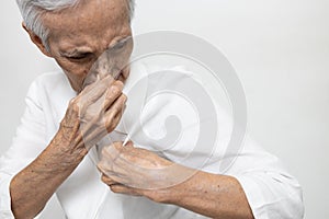 Armpit smelly or the body odor foul,Asian senior woman holding breath with fingers on nose,old elderly sniffing her wet armpit, photo