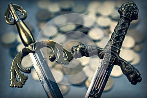 The arms of ancient knightly swords on the background of a scattering of coins. photo