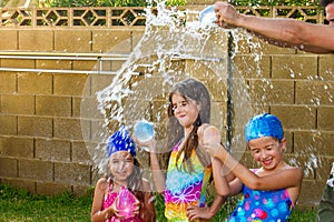 The Arms of a Father Break a Water Balloon Over the Heads of His