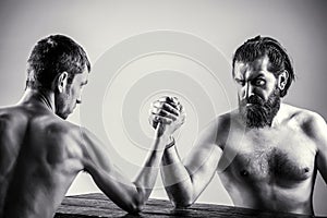 Arms wrestling thin hand, big strong arm in studio. Two man`s hands clasped arm wrestling, strong and weak, unequal