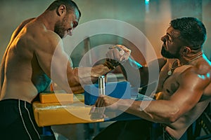 The Armwrestling. Two strong athletes in the gym compete in arm wrestling. Bodybuilders armwreslers in athletic training