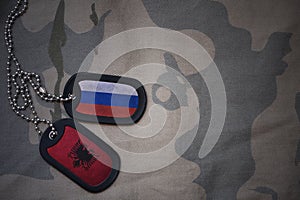 army blank, dog tag with flag of russia and albania on the khaki texture background.