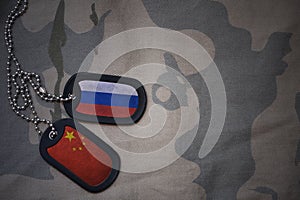 army blank, dog tag with flag of russia and china on the khaki texture background.