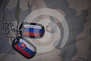 Army blank, dog tag with flag of russia and slovakia on the khaki texture background.