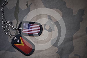 army blank, dog tag with flag of united states of america and east timor on the khaki texture background.