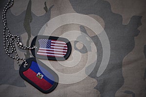 army blank, dog tag with flag of united states of america and haiti on the khaki texture background.