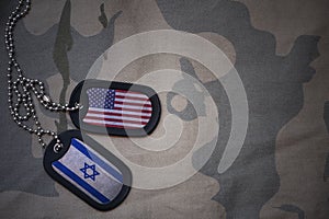 army blank, dog tag with flag of united states of america and israel on the khaki texture background.