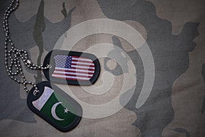 army blank, dog tag with flag of united states of america and pakistan on the khaki texture background.