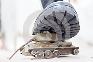 An army boot steps on a damaged toy tank