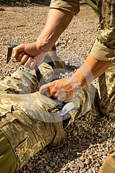 Army medics practice applying a tourniquet to the leg of a wounded soldier.
