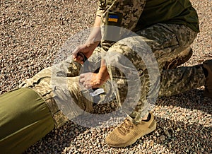 Army medics practice applying a tourniquet to the leg of a wounded soldier.