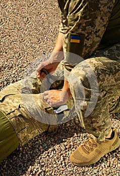 Army medics practice applying a tourniquet to the leg of a wounded soldier.