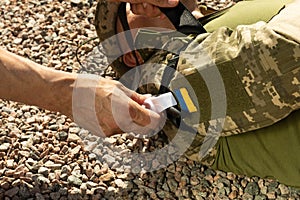 Army medics work out the imposition of a tourniquet on the forearm of a wounded soldier.