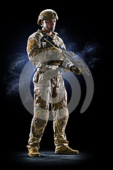 Army soldier in Protective Combat Uniform holding Special Operations Forces Combat Assault Rifle on dark background photo