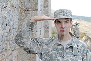 Army soldier saluting in front of a place in ruins