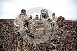 Army soldiers group on march in muddy field