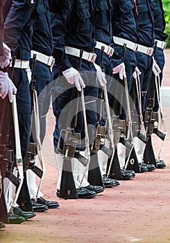 Army uniforms with machine guns in a row.