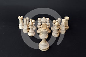 Army of wooden chess pieces led by the king on a dark background.