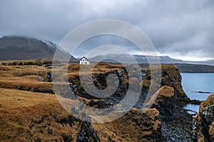 Arnarstapi coast with bizzar rock formation with a lonely white house, Iceland