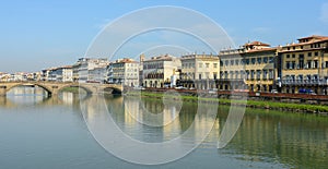 Arno River and the old promenade in Florence. Hazel houses with red roofs in Florence. Houses are reflected in the water